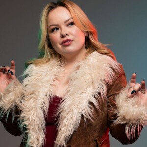 Nicola Coughlan posando con una chaqueta de piel sintética, mostrando una actitud confiada y estilosa
