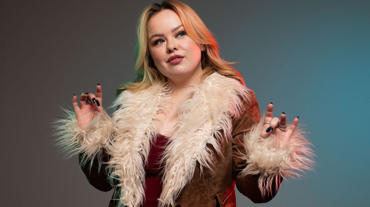 Nicola Coughlan posando con una chaqueta de piel sintética, mostrando una actitud confiada y estilosa
