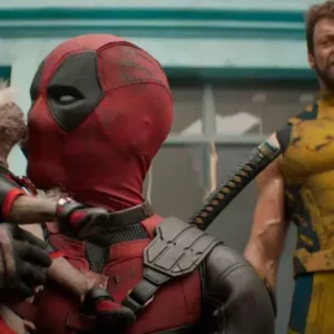 Deadpool (Ryan Reynolds) sosteniendo un cachorro mientras Wolverine (Hugh Jackman) observa en segundo plano con una expresión seria, ambos vestidos con sus trajes icónicos